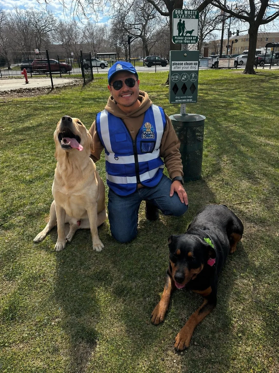 Paws and Scoops team member with dogs beside a commercial waste station